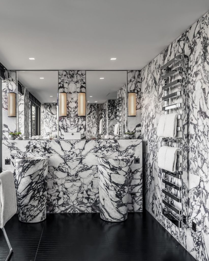 Bathroom inside a hotel with a black and white marble look on the walls and counters.