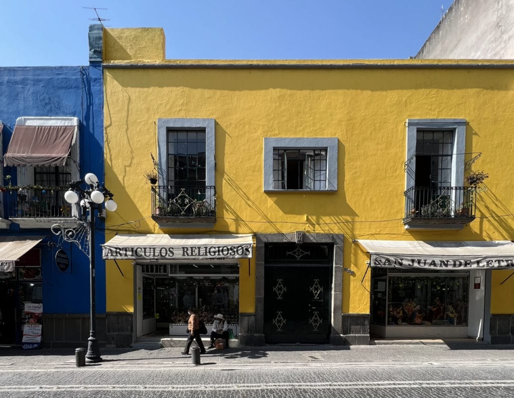 Yellow building in Puebla, Mexico with a person walking by.