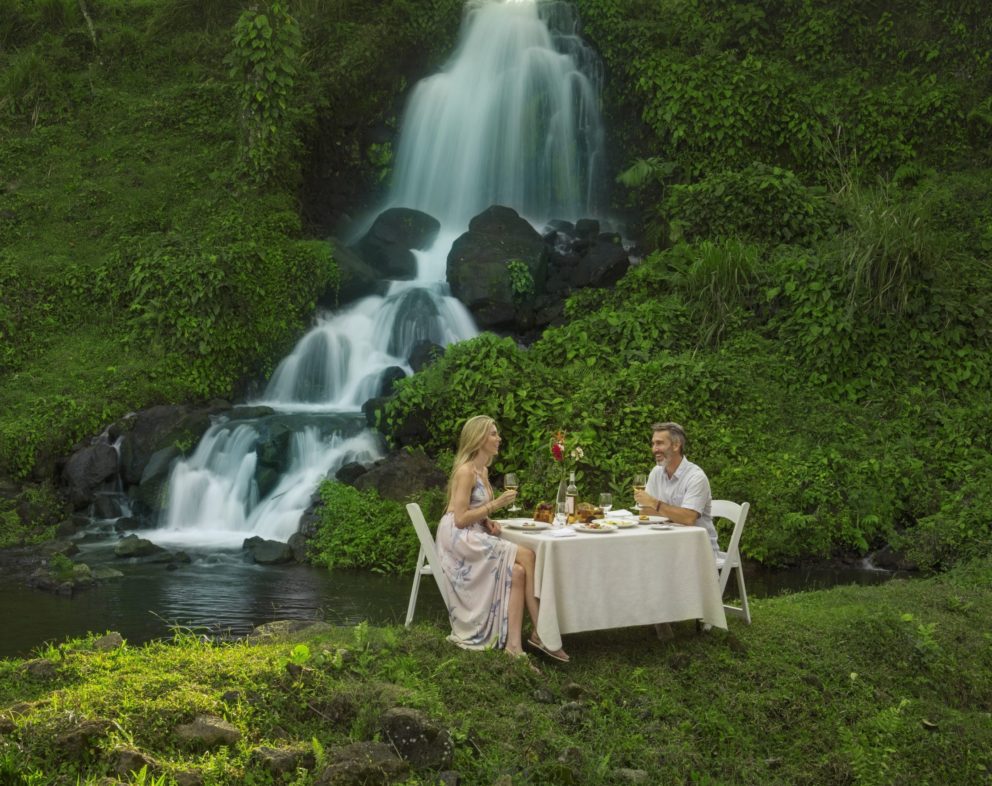 Two people eating next to a waterfall at Origins Lodge in Costa Rica.