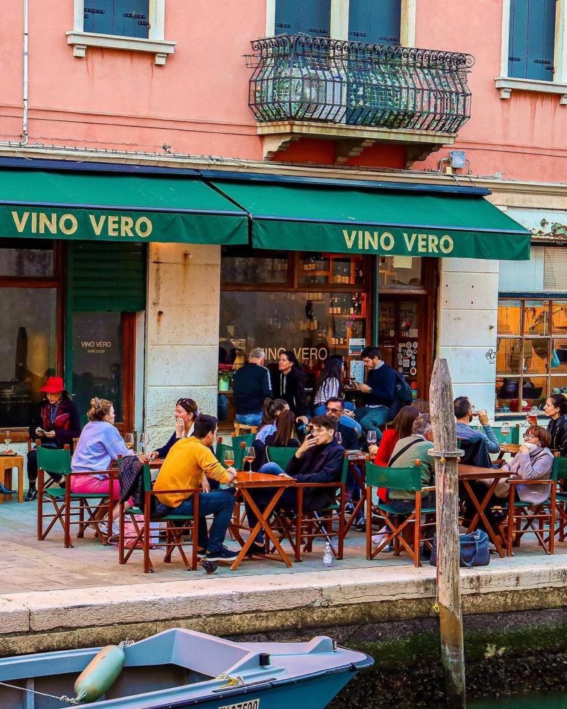 Outside of Vino Vero in Venice. There are many people sitting outside and drinking.