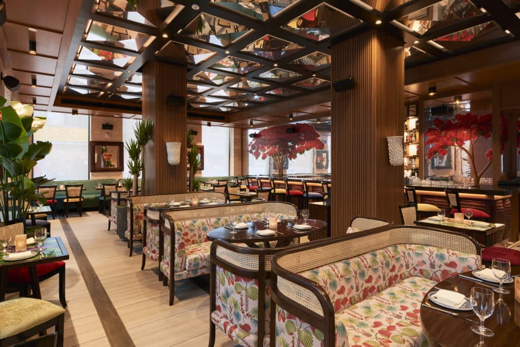 Inside of a restaurant with floral patterned booths, wooden tables, and wooden decor.