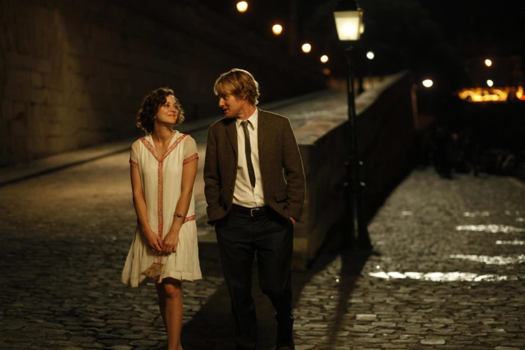 Scene from the movie Midnight in Paris where a man and woman are walking down a cobblestone street.