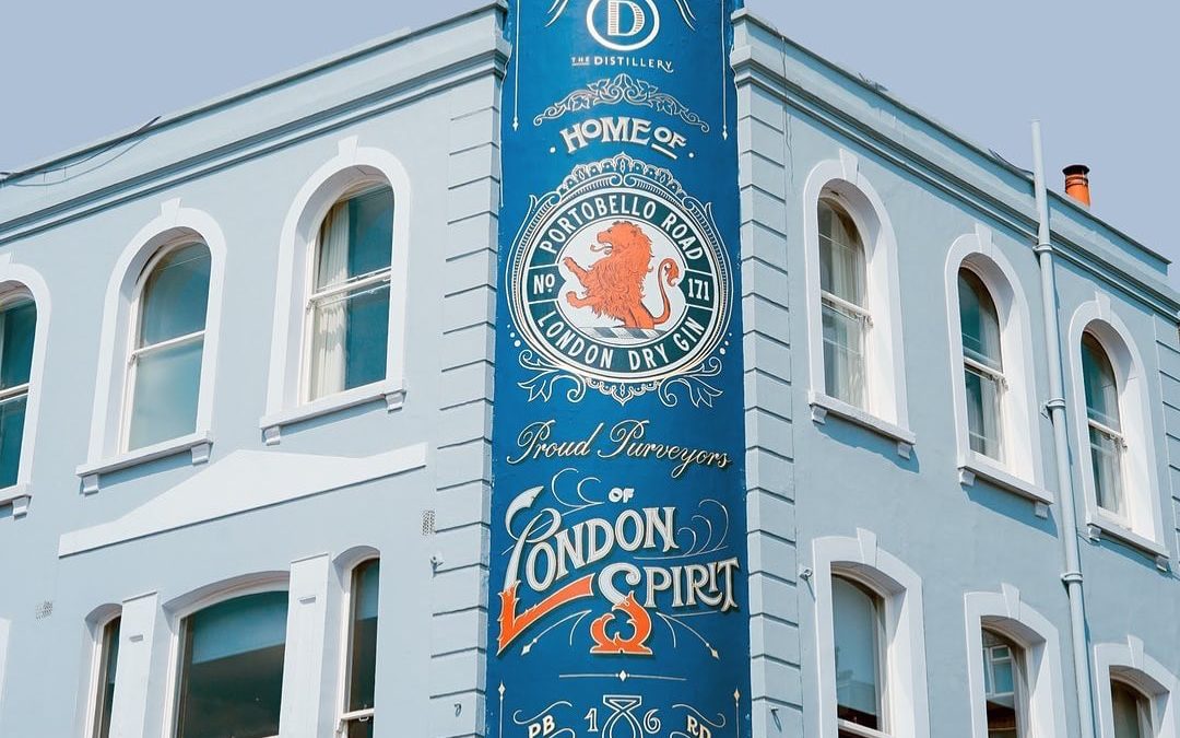 Outside of The Distillery London. The building is blue and features a large blue sign wrapped around the building.