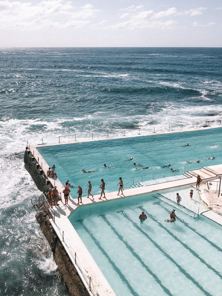 People entering and exiting the ocean to go to a pool that is in the middle of the ocean.