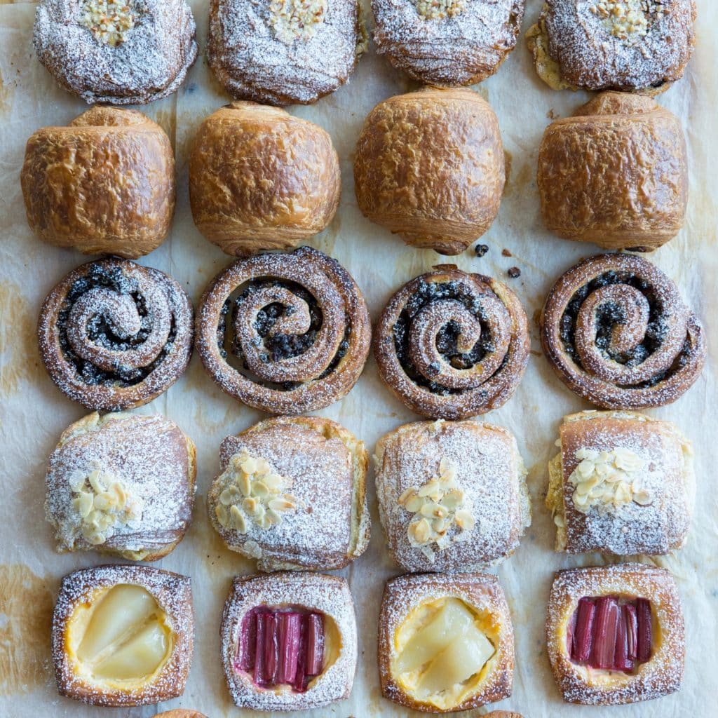 Various types of pastry lined up in neat rows on a piece of parchment-like paper.