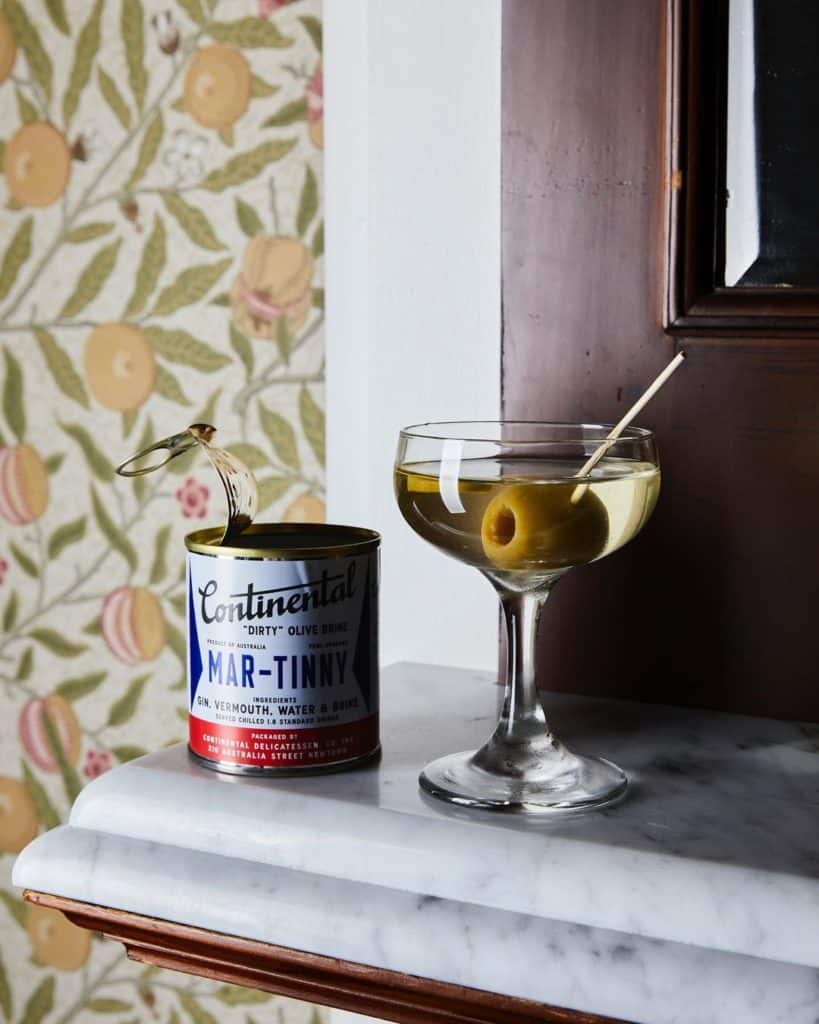 Martini with a green olive in it and a tin can with the name "Mar-tinny" on it.