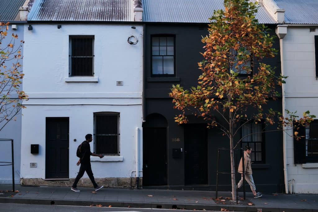 Two people walking by black and white buildings.