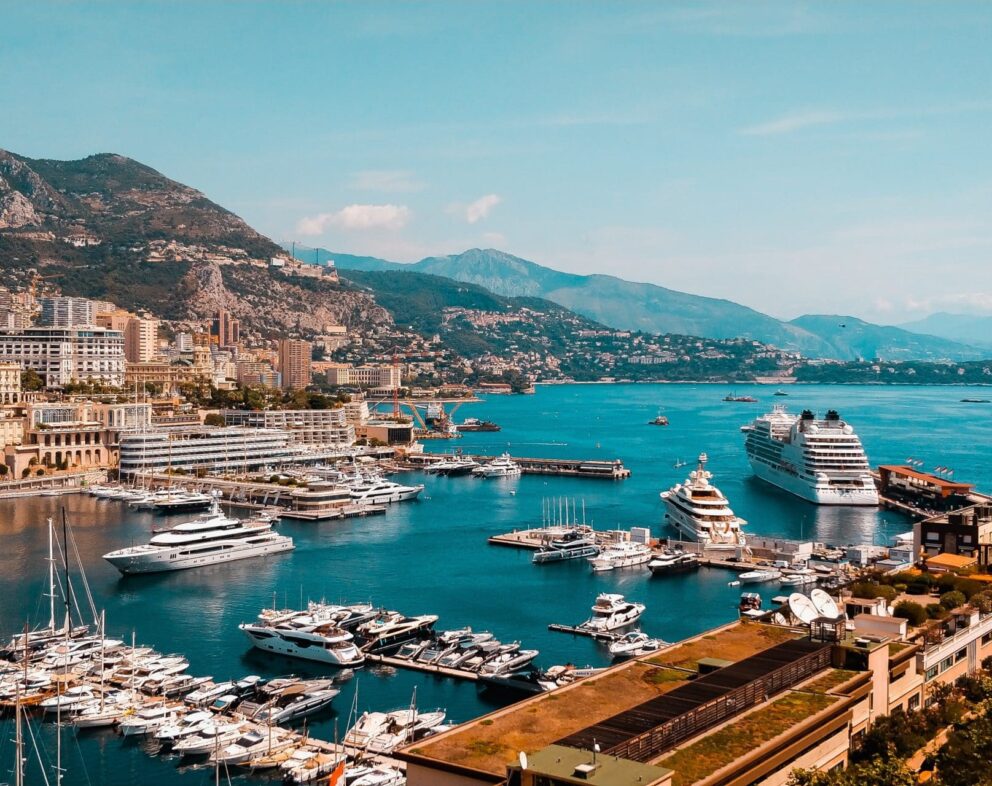 Panoramic view of Monaco. There are ships in the bay and mountains in the background.