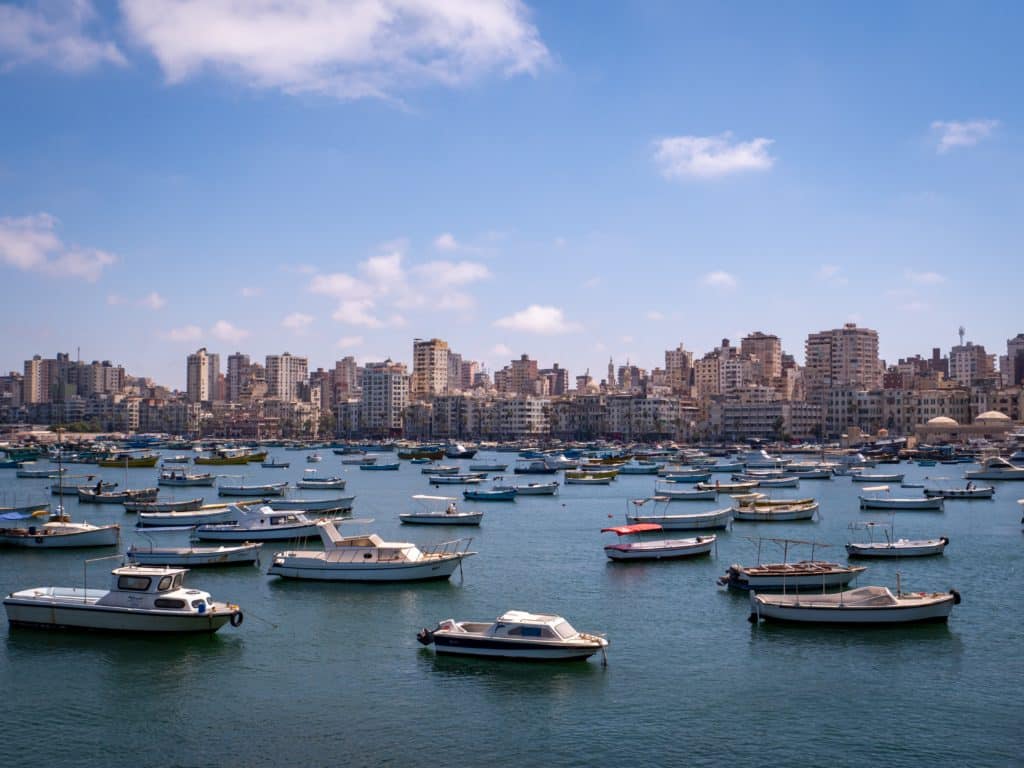 Body of water in Egypt with numerous boats on it and a city in the background.