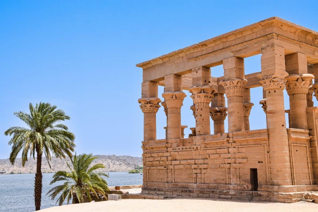 Old building in Egypt with many columns near a body of water.