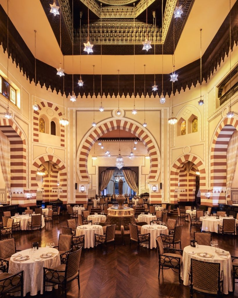 Inside of a restaurant in Egypt with many tables and chairs, as well as circular archways.