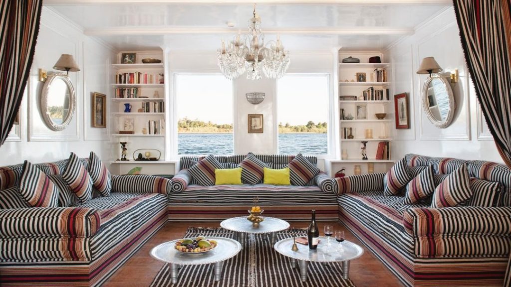 Three striped sofas in a room. The room is overlooking a body of water.