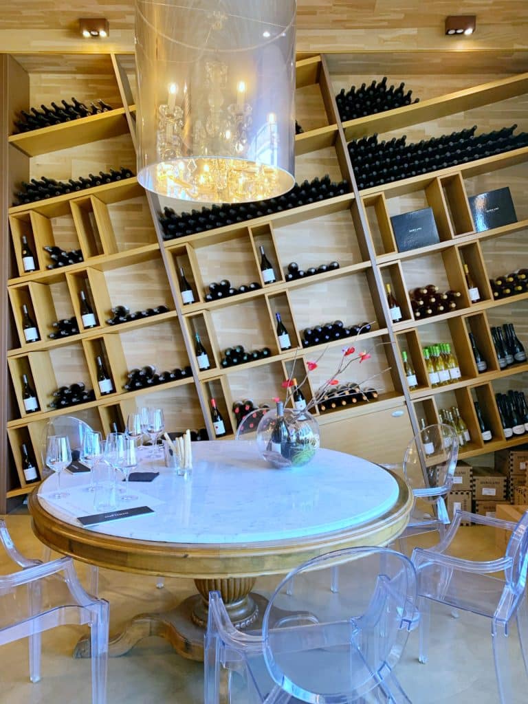 Table at a restaurant in Italy with numerous bottles of wine on the wall behind it.